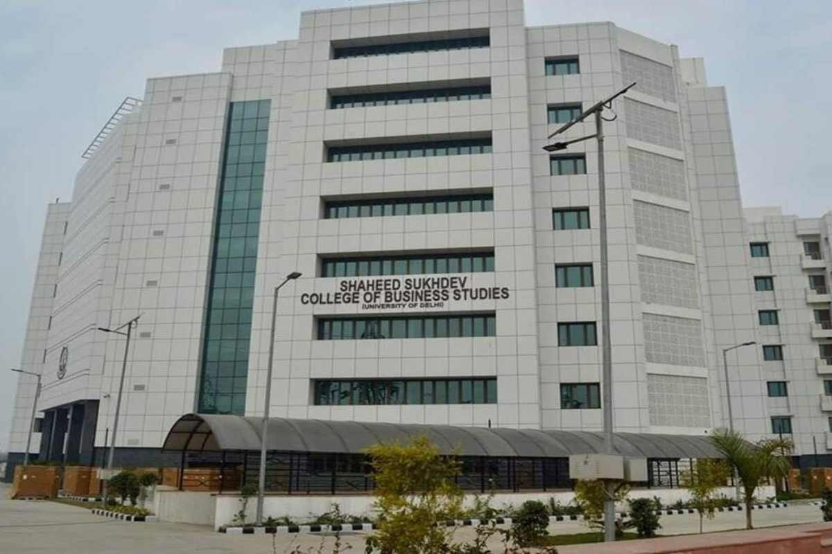 Front facade of Shaheed Sukhdev College of Business Studies, a modern white campus building with a curved entrance canopy and landscaping.